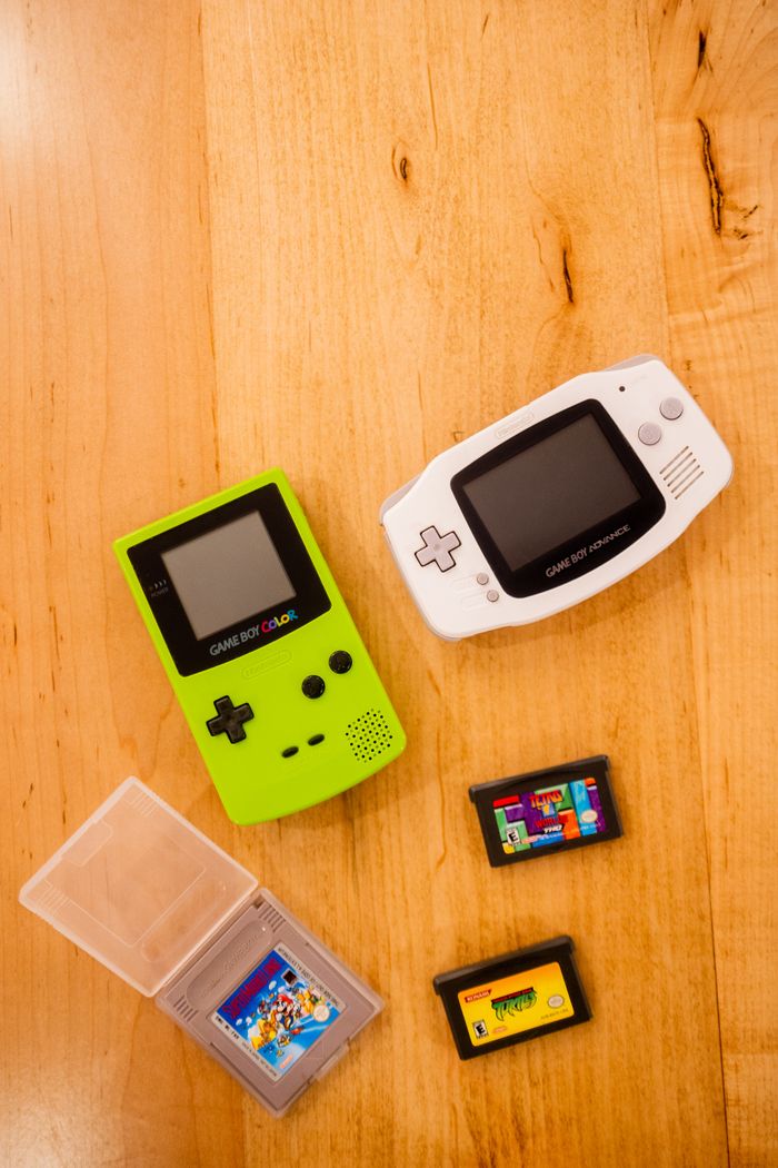 Top view of classic Game Boys and cartridges on wooden background, showcasing gaming nostalgia.