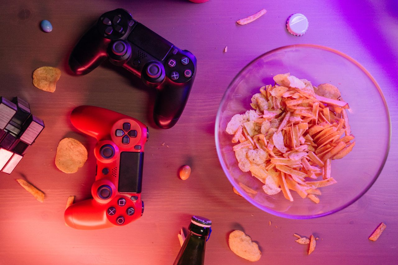 Overhead view of game controllers and snacks on a table, perfect for a gaming night setup.