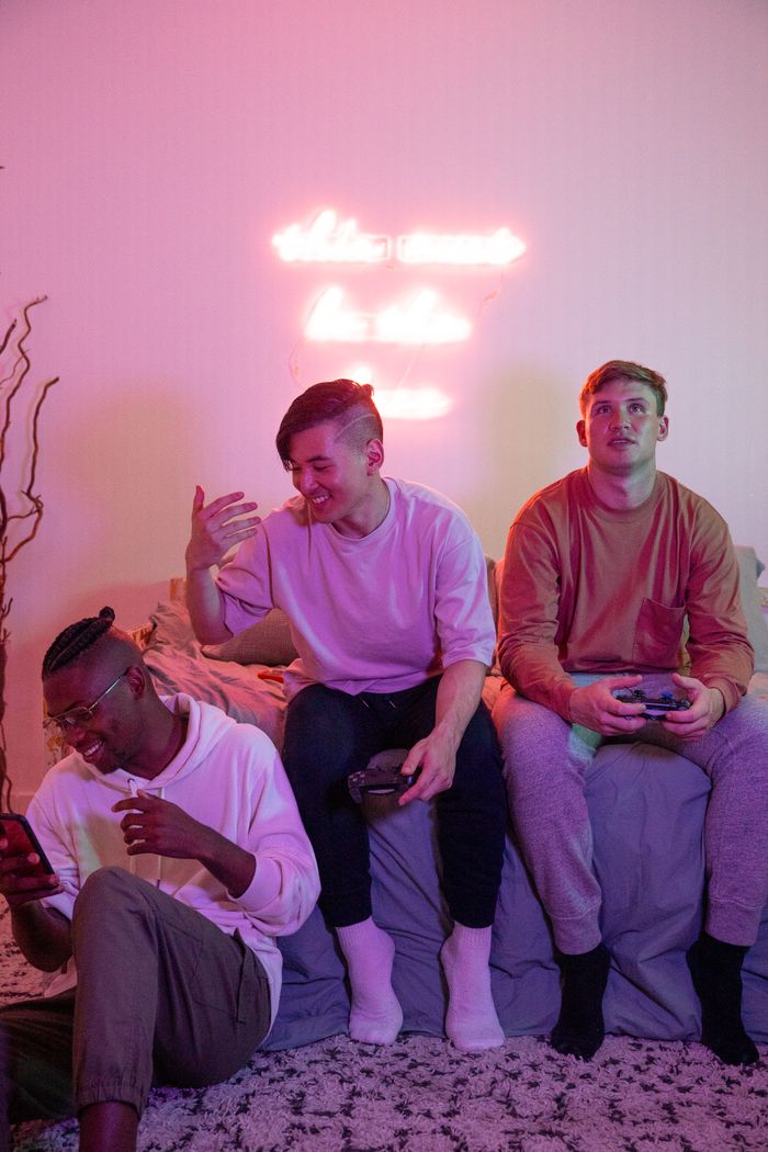 Group of young men having fun playing video games under neon lights.